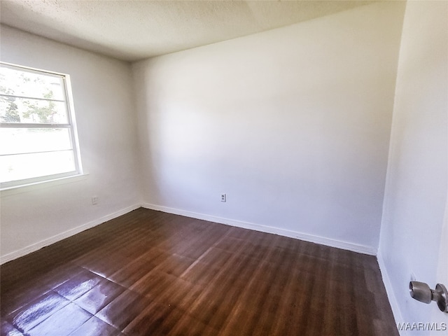 spare room with a textured ceiling and dark hardwood / wood-style floors