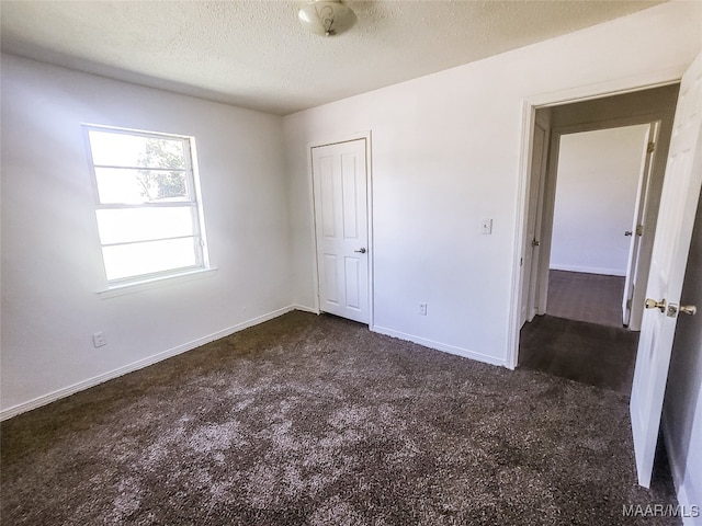 unfurnished bedroom featuring dark carpet and a textured ceiling