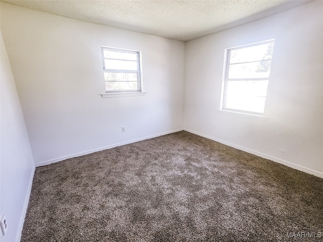 spare room with a textured ceiling and dark carpet