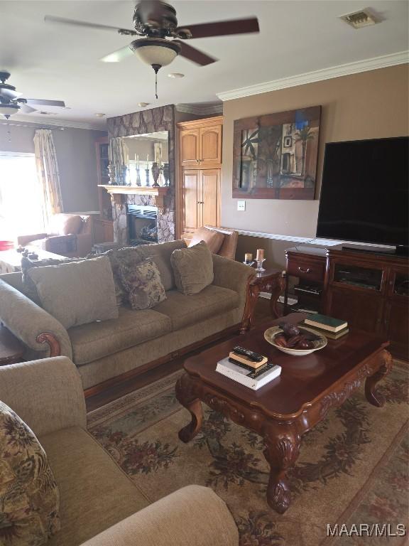 living room with ceiling fan, a fireplace, and crown molding