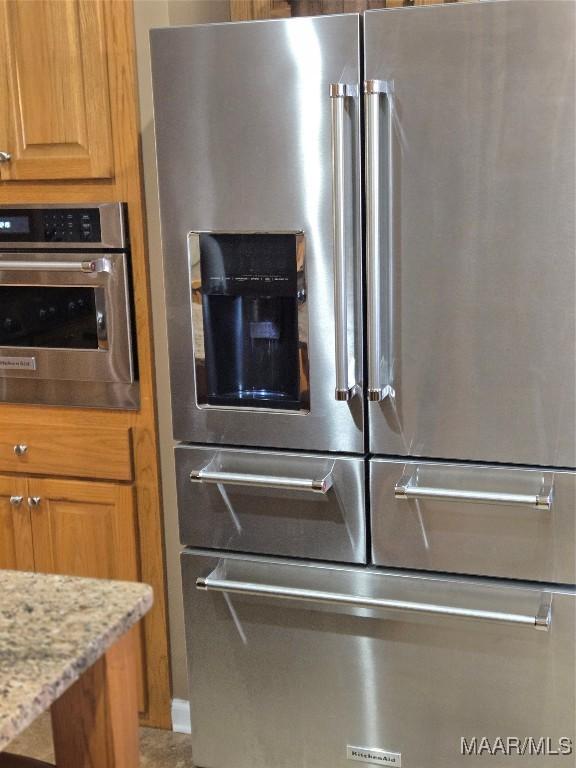 interior details with light stone countertops and appliances with stainless steel finishes