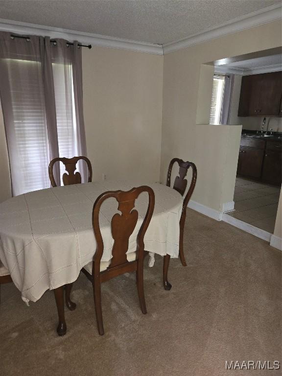 dining area featuring a textured ceiling, crown molding, carpet flooring, and sink