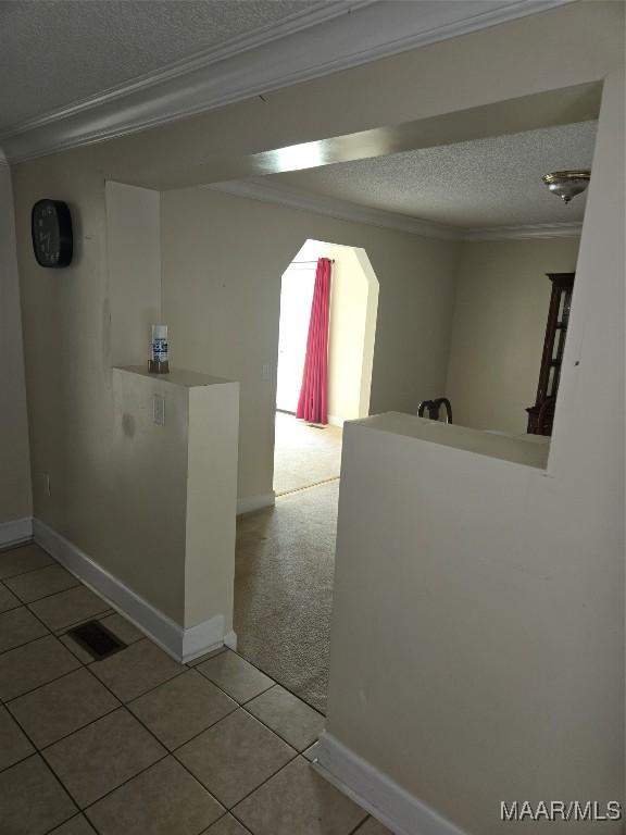 hall featuring ornamental molding, a textured ceiling, and light tile patterned flooring