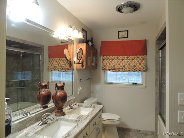 full bathroom with vanity, enclosed tub / shower combo, toilet, and plenty of natural light