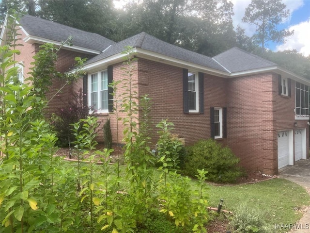 view of property exterior with a garage, driveway, and brick siding