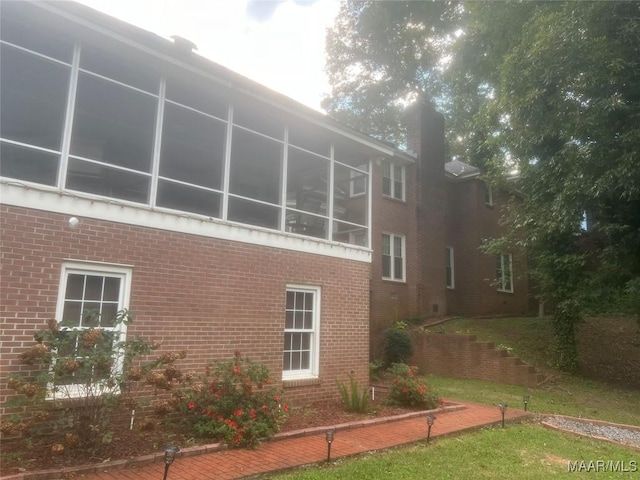 view of side of home with a sunroom and brick siding