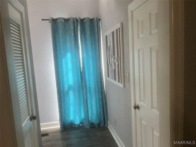 empty room with dark wood-type flooring, visible vents, and baseboards