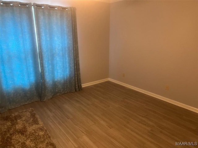 empty room featuring dark wood-style flooring and baseboards