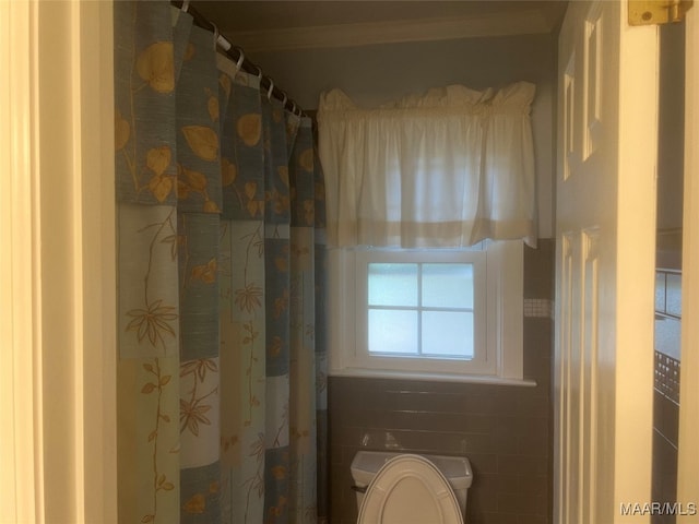 bathroom featuring toilet, tile walls, and a shower with shower curtain