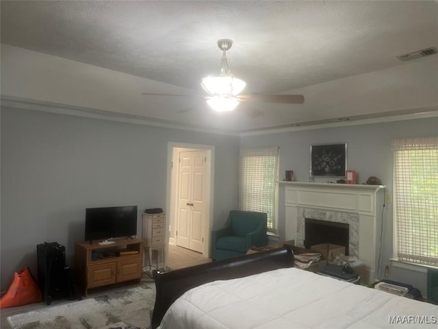 bedroom with a premium fireplace, visible vents, and a ceiling fan