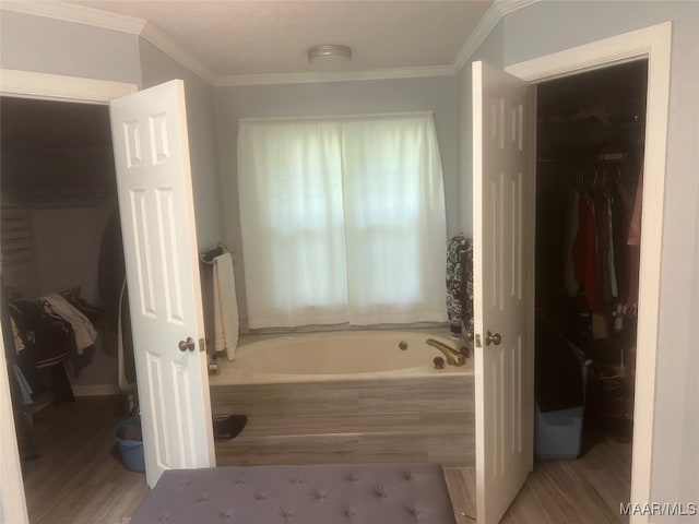 bathroom with ornamental molding, a tub to relax in, and hardwood / wood-style flooring