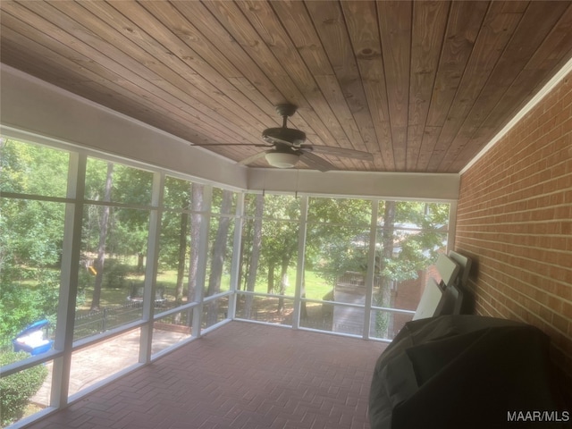 unfurnished sunroom featuring ceiling fan, a healthy amount of sunlight, and wooden ceiling