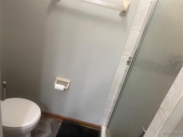 full bathroom featuring a stall shower, toilet, and baseboards