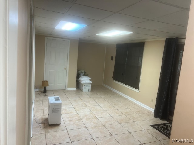 empty room featuring a paneled ceiling and light tile patterned floors