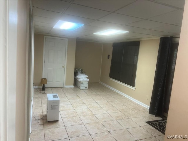 bathroom featuring baseboards, a drop ceiling, and tile patterned floors