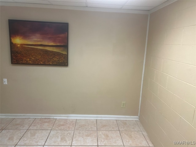 tiled spare room featuring crown molding