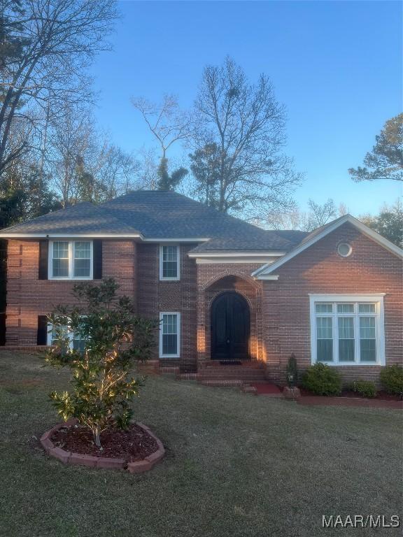 view of front facade featuring brick siding and a front yard