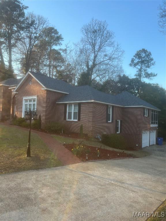 view of home's exterior with concrete driveway, an attached garage, and a shingled roof