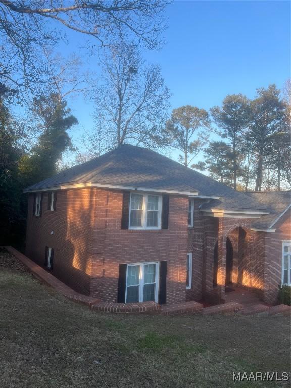 view of side of home with a yard and brick siding