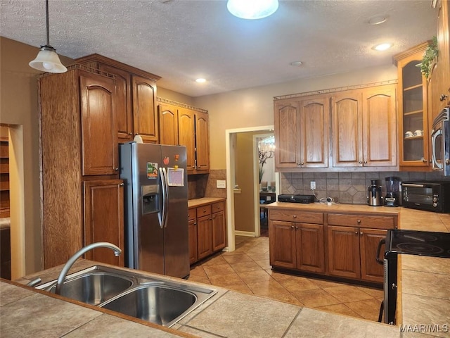 kitchen with sink, decorative light fixtures, decorative backsplash, tile counters, and stainless steel appliances