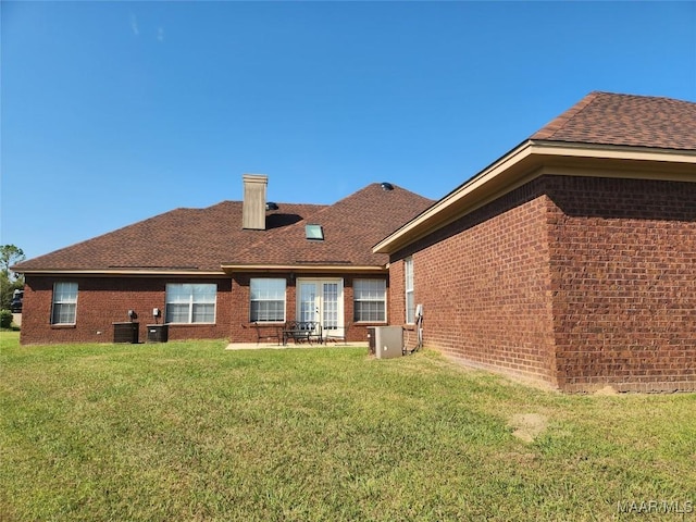 rear view of house featuring a lawn and cooling unit