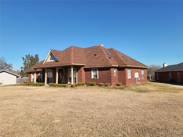 rear view of property featuring central AC unit and a lawn