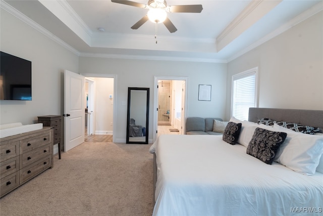 carpeted bedroom featuring ornamental molding, a tray ceiling, connected bathroom, and ceiling fan