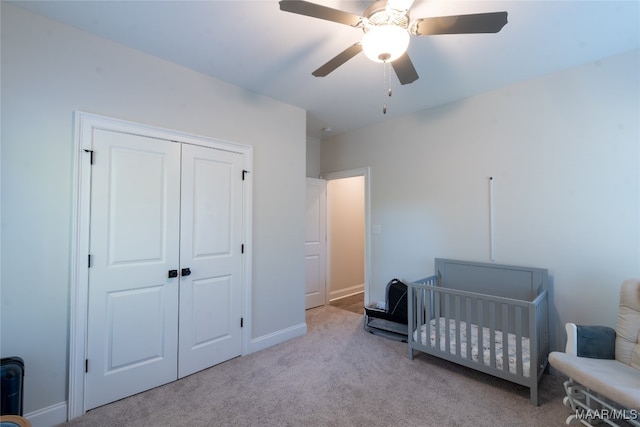 carpeted bedroom featuring ceiling fan, a nursery area, and a closet