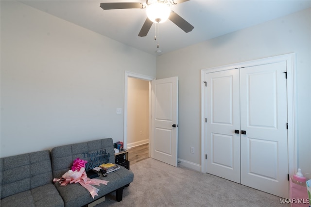 living area with light carpet and ceiling fan