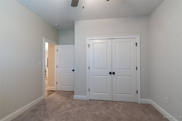 unfurnished bedroom featuring ceiling fan, a closet, and light colored carpet