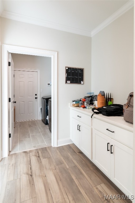 bar featuring washing machine and clothes dryer, crown molding, light wood-type flooring, and white cabinetry