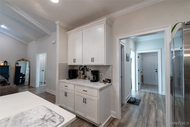 kitchen featuring backsplash, white cabinetry, crown molding, vaulted ceiling, and dark hardwood / wood-style flooring