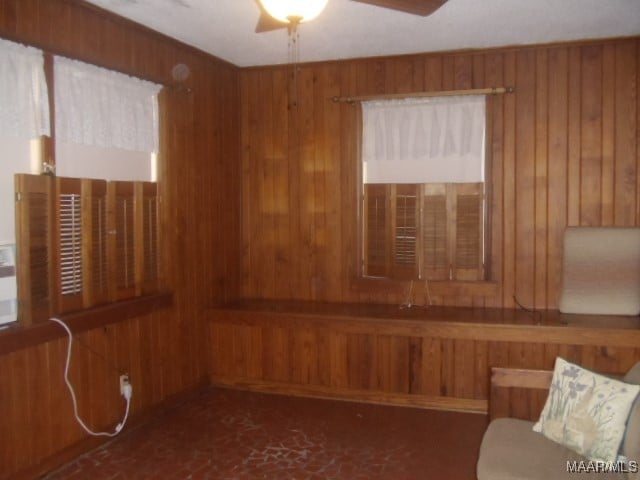 empty room featuring wood walls and ceiling fan