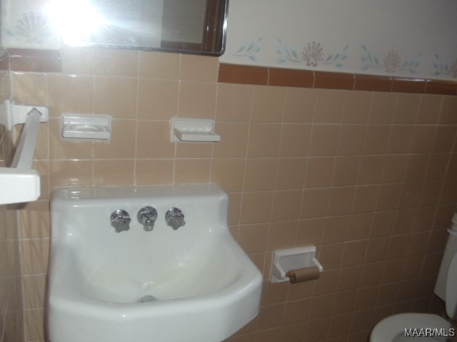 bathroom featuring tile walls and toilet