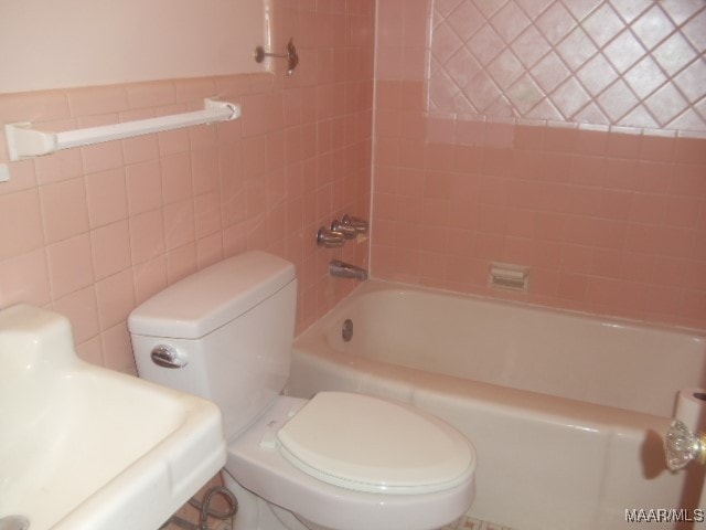 bathroom featuring tile walls, shower / tub combination, and toilet