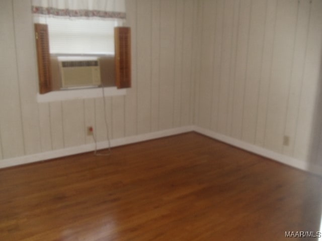 empty room featuring cooling unit and dark wood-type flooring