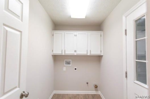 clothes washing area with a textured ceiling, light hardwood / wood-style flooring, cabinets, hookup for a washing machine, and electric dryer hookup