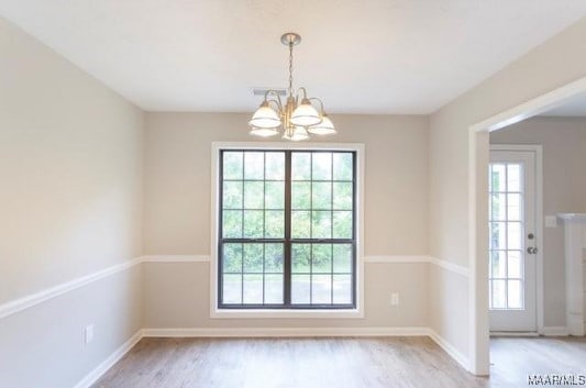 unfurnished room with light hardwood / wood-style floors and a chandelier