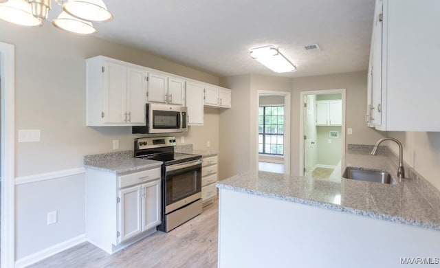 kitchen featuring sink, a notable chandelier, white cabinets, appliances with stainless steel finishes, and light stone countertops