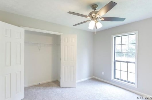 unfurnished bedroom featuring a closet, ceiling fan, and light colored carpet