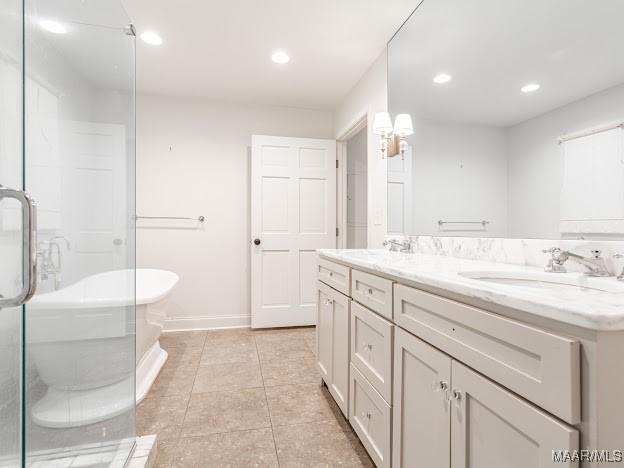bathroom with baseboards, a sink, a soaking tub, double vanity, and tile patterned flooring