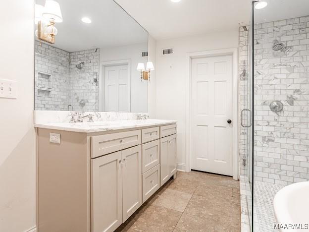 full bath with visible vents, double vanity, a stall shower, and recessed lighting
