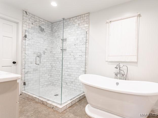 full bath with a shower stall, recessed lighting, vanity, and a soaking tub