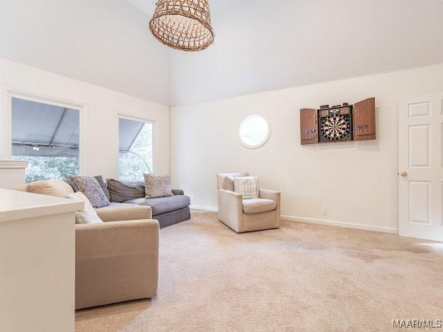 living area with high vaulted ceiling, light carpet, and baseboards