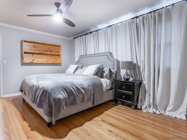 bedroom featuring crown molding, wood finished floors, baseboards, and a ceiling fan