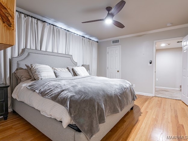 bedroom with light hardwood / wood-style floors, ornamental molding, and ceiling fan