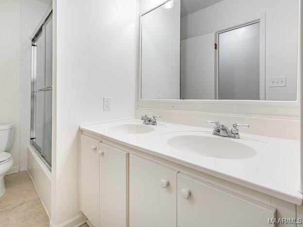 full bath with combined bath / shower with glass door, double vanity, a sink, and toilet