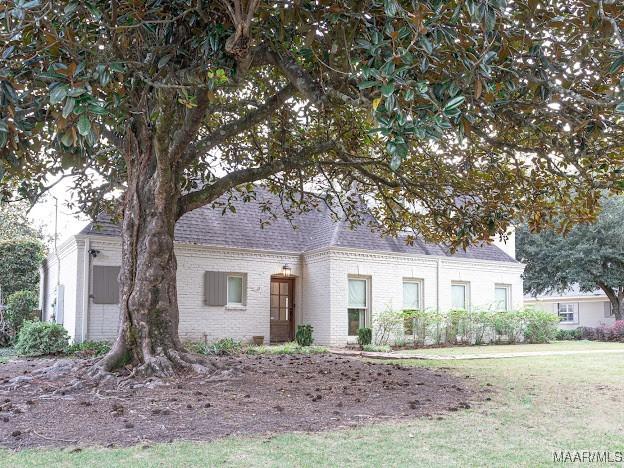 view of front of property with roof with shingles, a front yard, and brick siding
