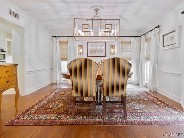 sitting room featuring crown molding, wood finished floors, an inviting chandelier, and visible vents