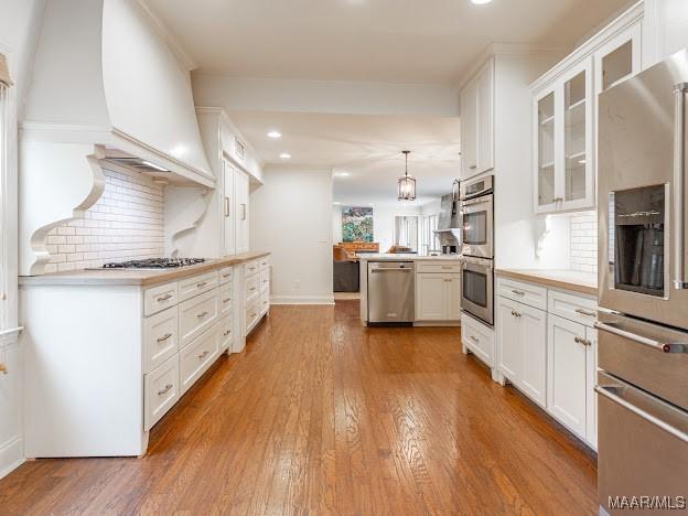 kitchen featuring tasteful backsplash, appliances with stainless steel finishes, wood finished floors, and glass insert cabinets